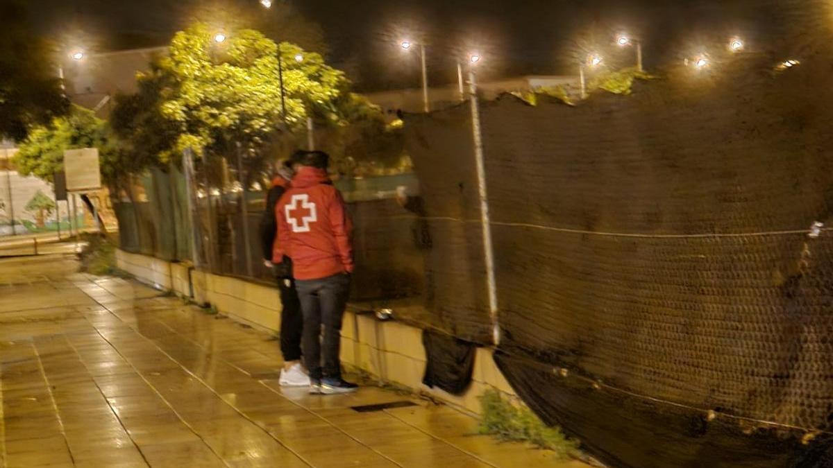 Dos voluntarios de Cruz Roja atienden a una persona sin hogar en Alzira.