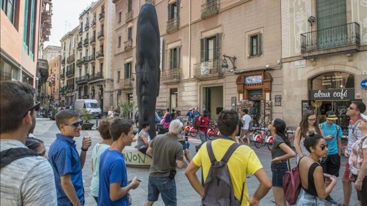 Un grupo de turistas junto a 'Carmela', la escultura de Plensa que hay frente al Palau de la Música.