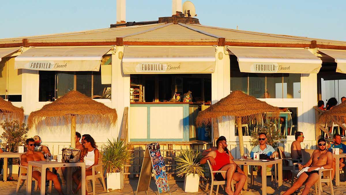 Chiringuitos y kioscos de playa, restaurantes, terrazas al sol junto al mar en la arena