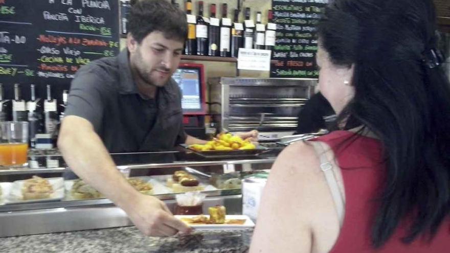 Un camarero sirve una tapa en La esquina de Colás.