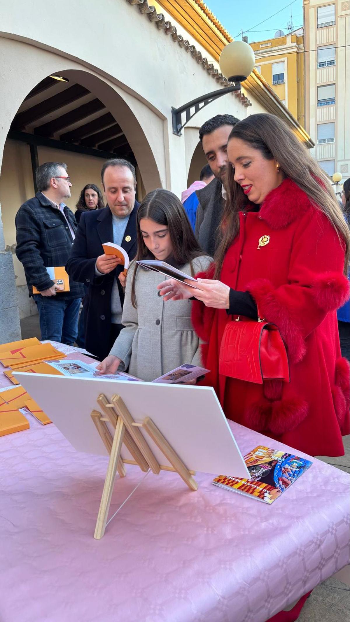 La fallera mayor ojeando los llibrets junto al alcalde