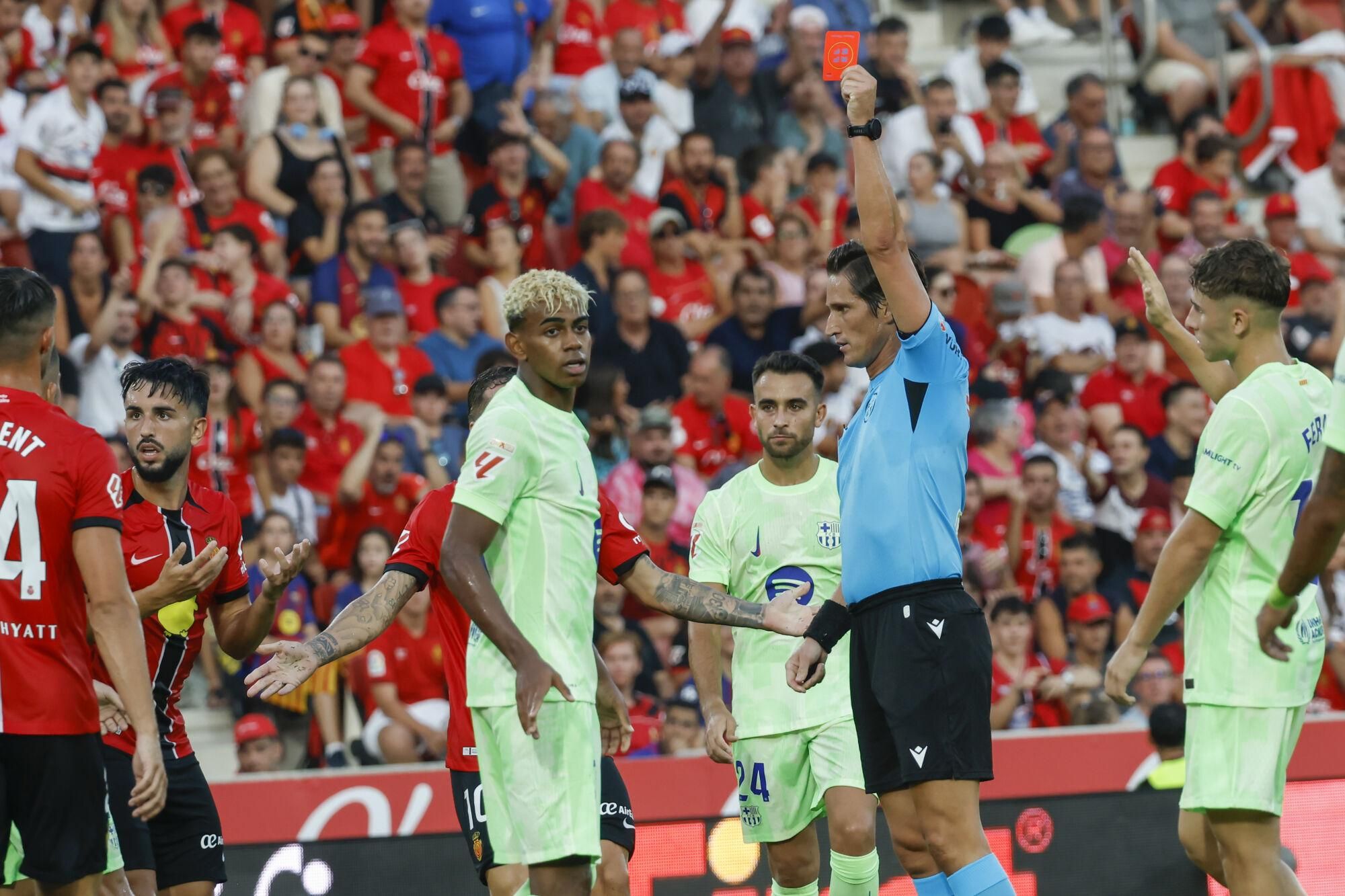 PALMA DE MALLORCA, 16/08/2025.- El árbitro del encuentro José Luis Munuera (d) saca tarjeta roja a Manu Morlanes (i) del Mallorca este sábado, durante la primera jornada de LaLiga EA Sports, entre el RCD Mallorca y el FC Barcelona, en el estadio de Son Moix de Palma de Mallorca. EFE/ Cati Cladera