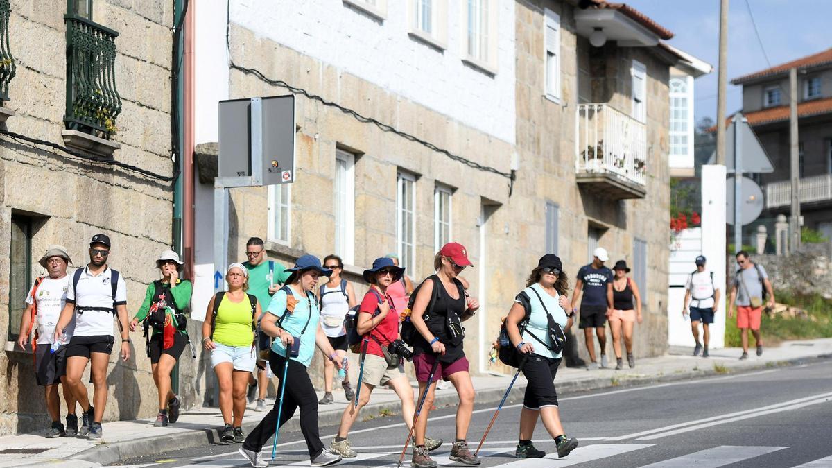 Un grupo de peregrinos cruza un paseo de peatones.