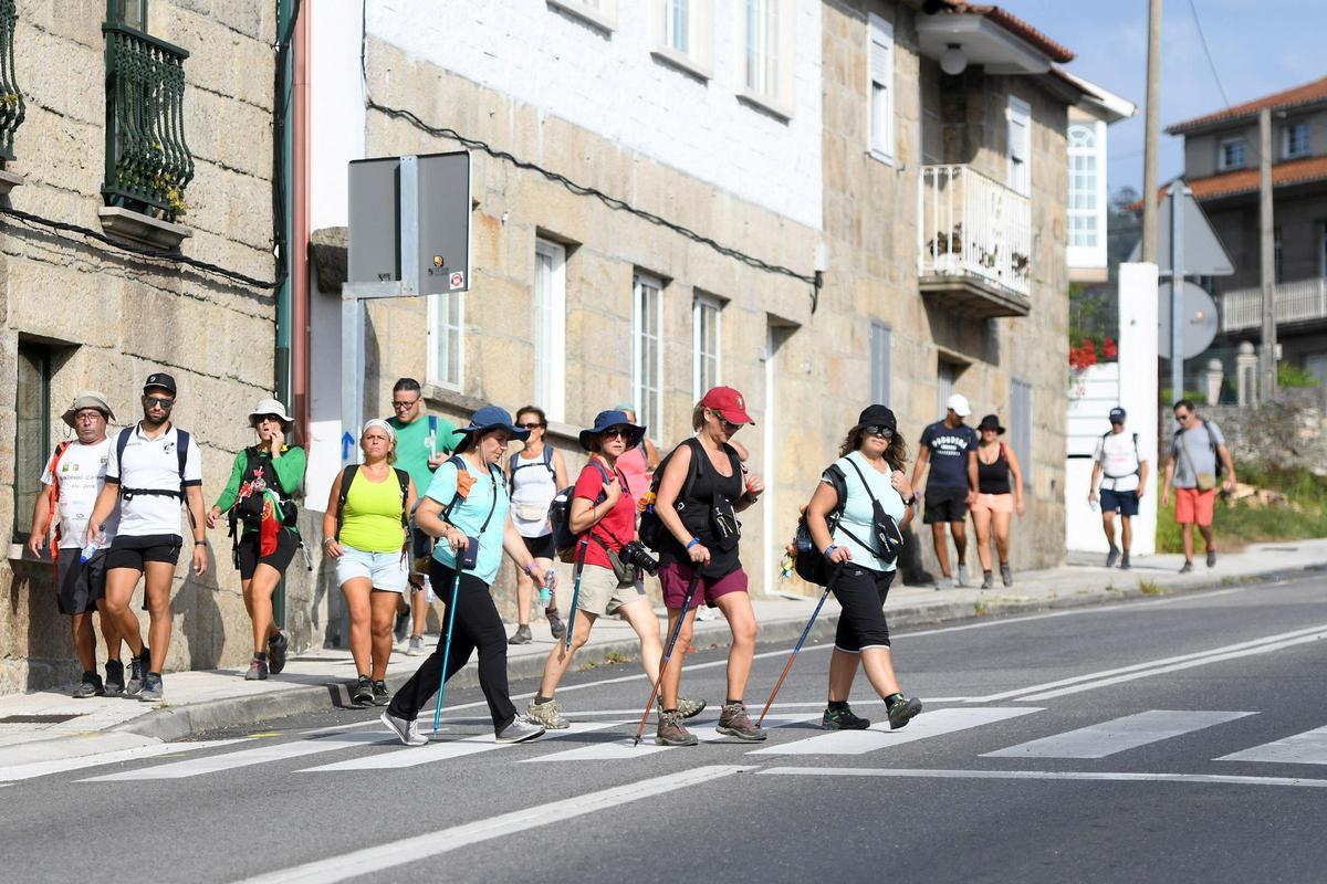 Un grupo de peregrinos cruza un paseo de peatones.