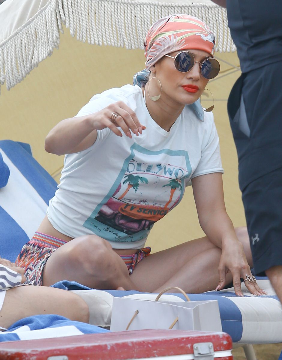 Jennifer López con pañuelo en la cabeza, gafas de sol y joyas para tomar el sol