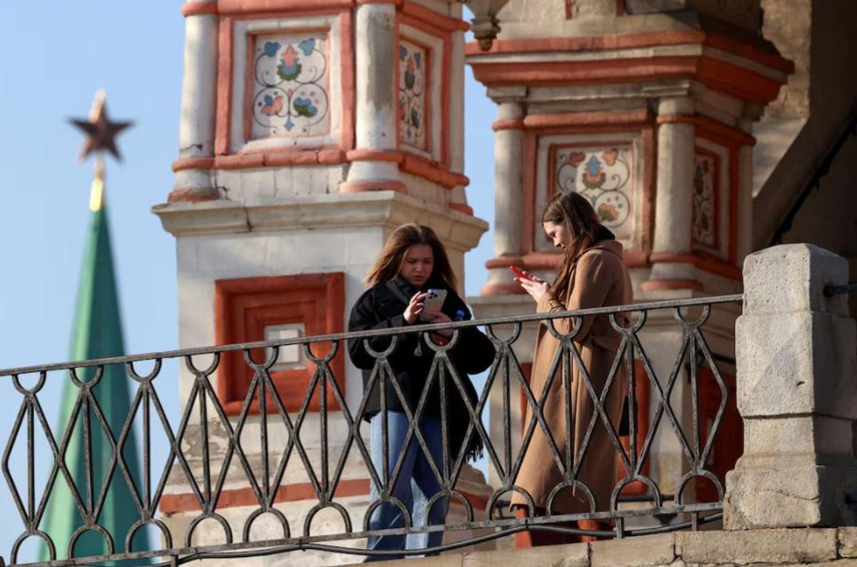 Varias personas utilizan sus teléfonos móviles mientras están de pie frente a la catedral de San Basilio en el centro de Moscú, Rusia.