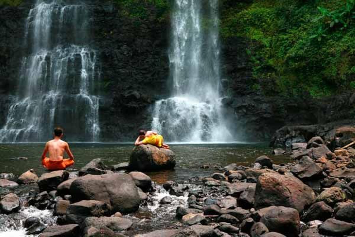 Monjes budistas descansando a las orillas del Mekong con las en las cataratas Phasoume al fondo.