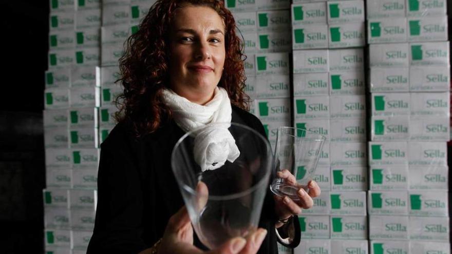 Mónica Bernardo sostiene dos vasos de sidra como los que exportarán a Japón.