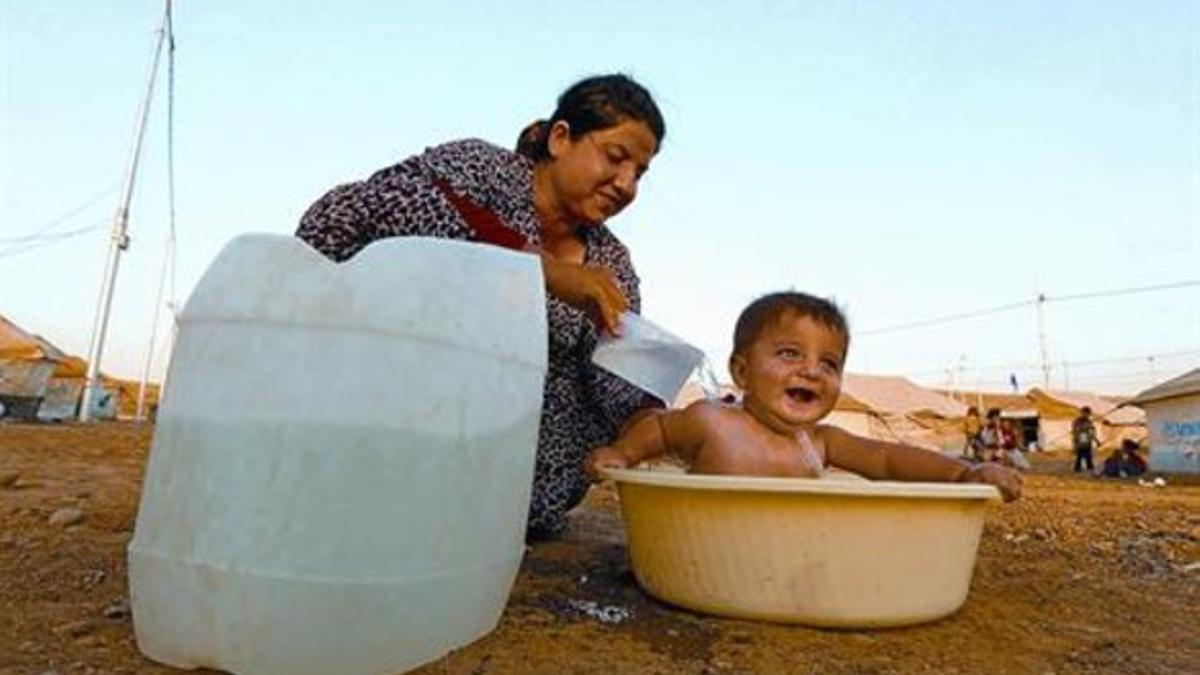 Una refugiada siria baña a un niño en el campo de Quru Gusik, en el Kurdistán iraquí, el pasado martes.