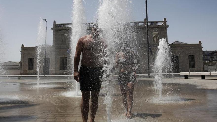 Dos jóvenes se refrescan en una fuente de la ciudad.