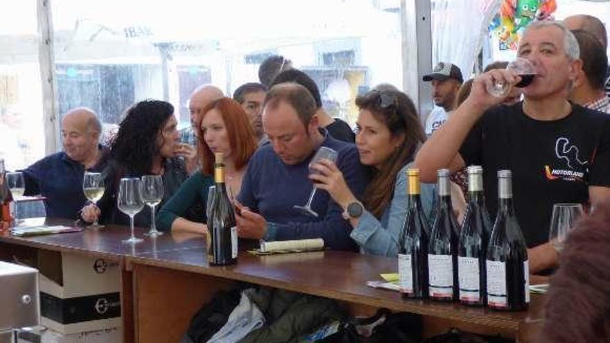 Los asistentes a la fiesta disfrutan de un vino en el expositor de las bodegas de la denominación de origen.