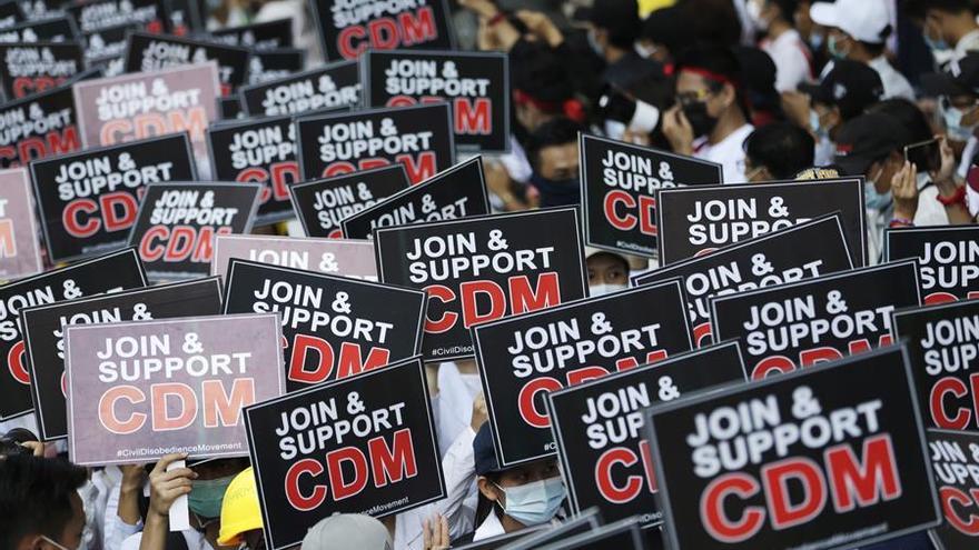 Manifestantes en Birmania muestran carteles que piden a los ciudadanos que se unan al movimiento de desobediencia civil.