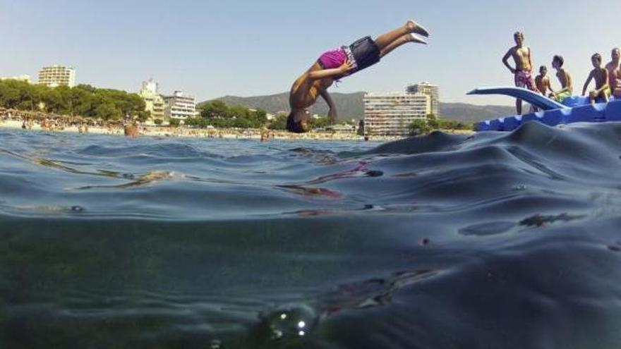 Jóvenes se zambullen en el agua desde una plataforma en Magaluf para combatir el tórrido calor veraniego.