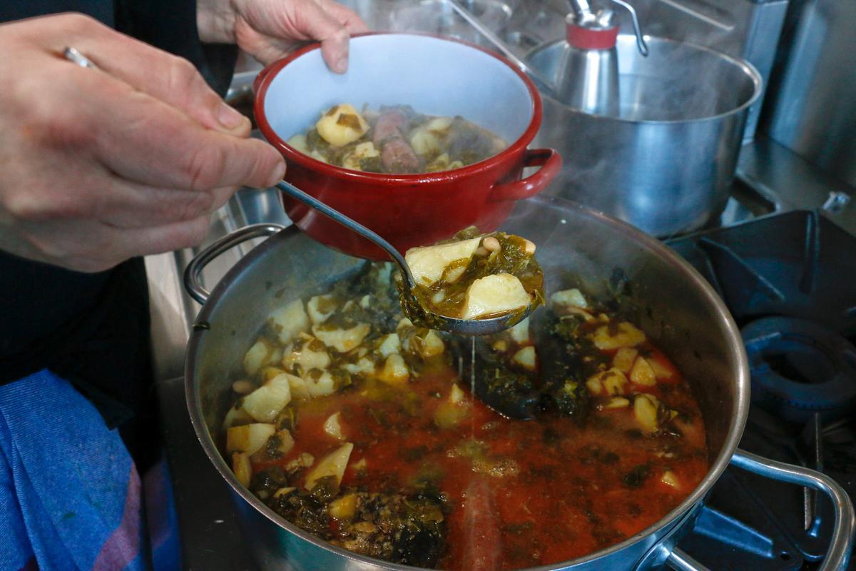 Preparando una cazuelina de pote asturiano, para ser servida a unos clientes.