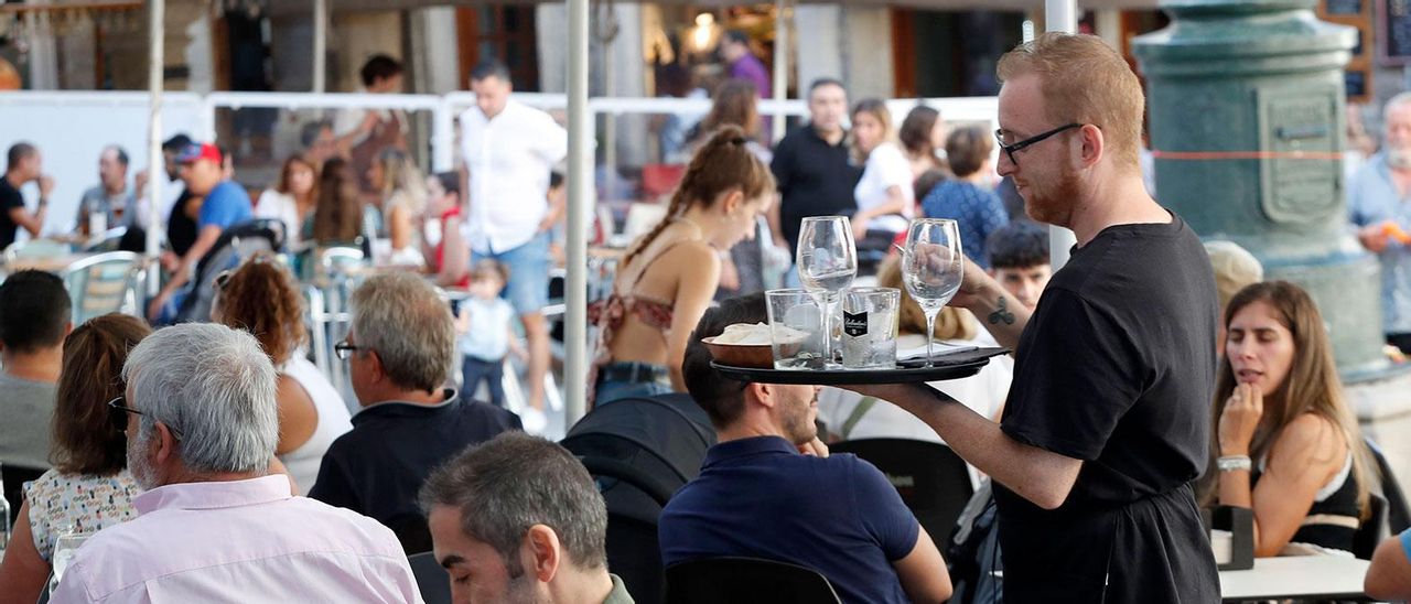Un camarero sirviendo en una terraza abarrotada en Vigo