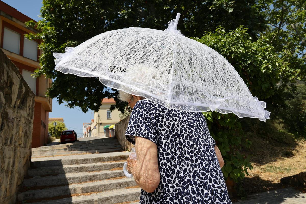 Una mujer se protege del sol con una sombrilla