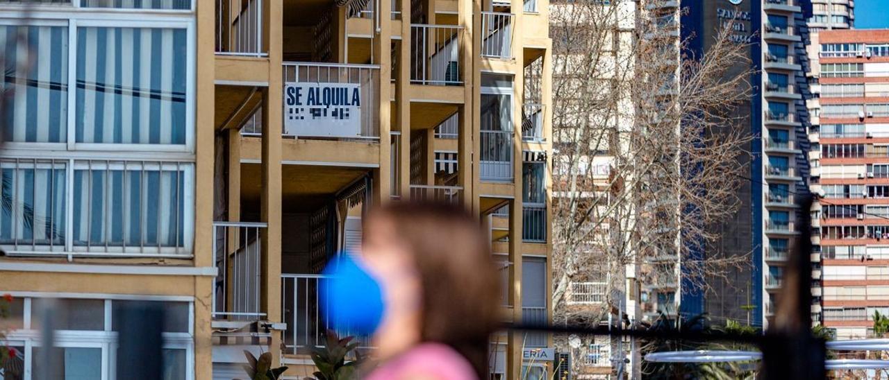 Una mujer pasa junto a un edificio donde se alquila una vivienda en Benidorm