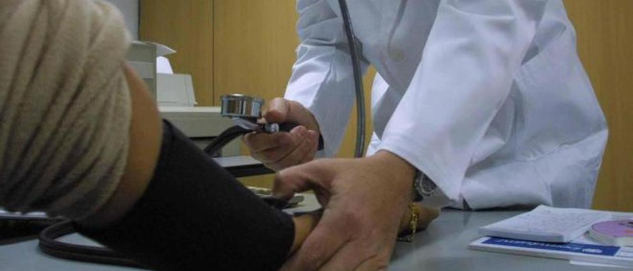 Un médico mide la tensión a un paciente en la consulta.