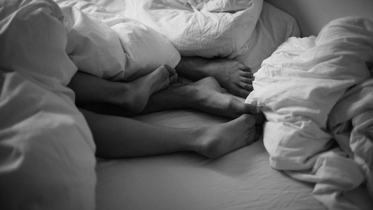Una pareja cruza sus pies en la cama.