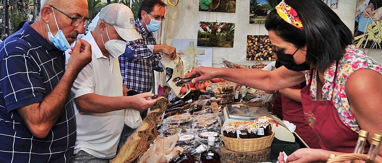 Una productora de dátil da a probar el fruto a varios visitantes en el arranque de la Fireta, ayer.  |