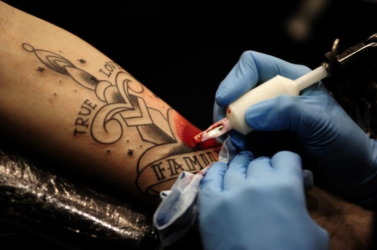 Un tatuador elabora un dibuix sobre la pell.