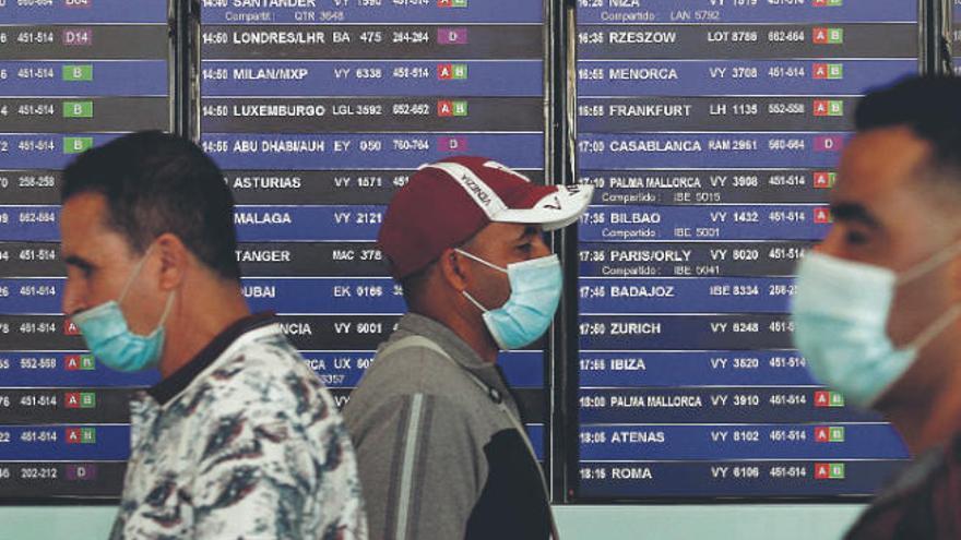 Pasajeros protegidos con mascarillas en el aeropuerto de Barcelona.