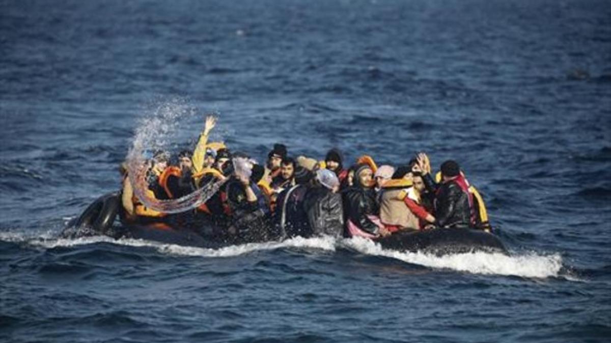 Un refugiado intenta achicar agua de su precaria embarcación a punto de inundarse con sus ocupantes a bordo, cerca de la isla de Lesbos, ayer.