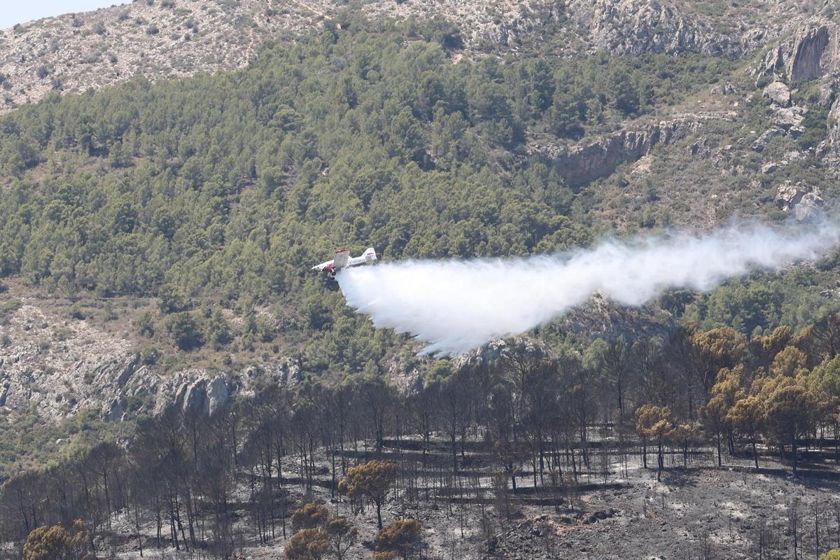 Imagen de archivo de una avioneta descargando agua para refrescar una zona ya calcinada con el fin de evitar que rebroten las llamas.