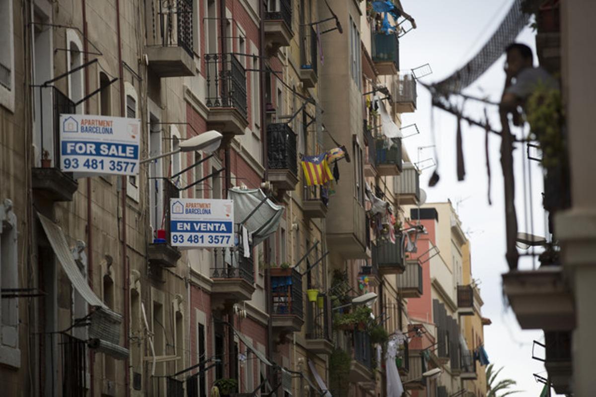 Anuncios de venta de pisos en castellano e inglés en una calle de la Barceloneta.