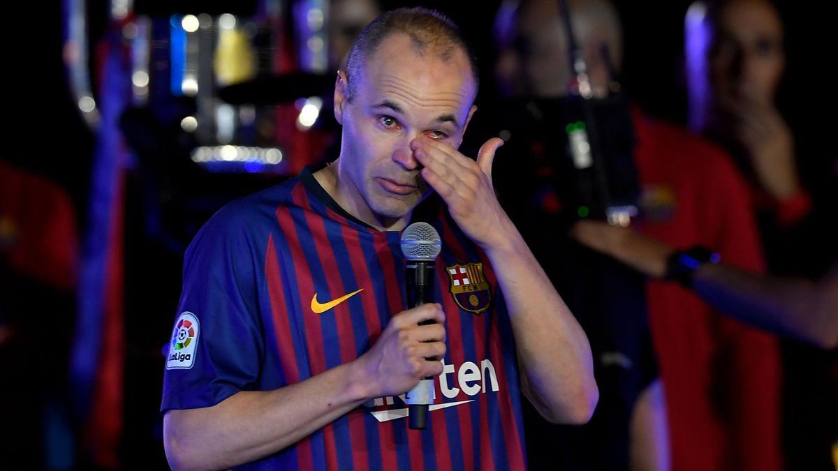 (FILES) In this file photo taken on May 20, 2018 Barcelona's Spanish midfielder Andres Iniesta wipes his tears as he addresses f