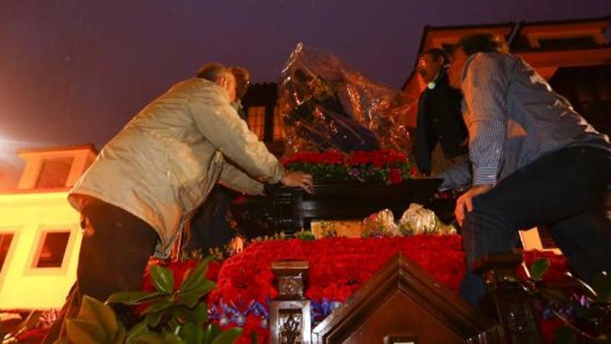 Arriba, el paso de la Dolorosa entre un mar de paraguas en El Parche. Debajo de estas líneas, los cofrades de Jesús de Galiana protegen el paso con un plástico; a la derecha, cofrades de San Juan Evangelista dentro de la iglesia una vez confirmada la suspensión de la procesión, y debajo, un nazareno bajo el agua. | mara villamuza