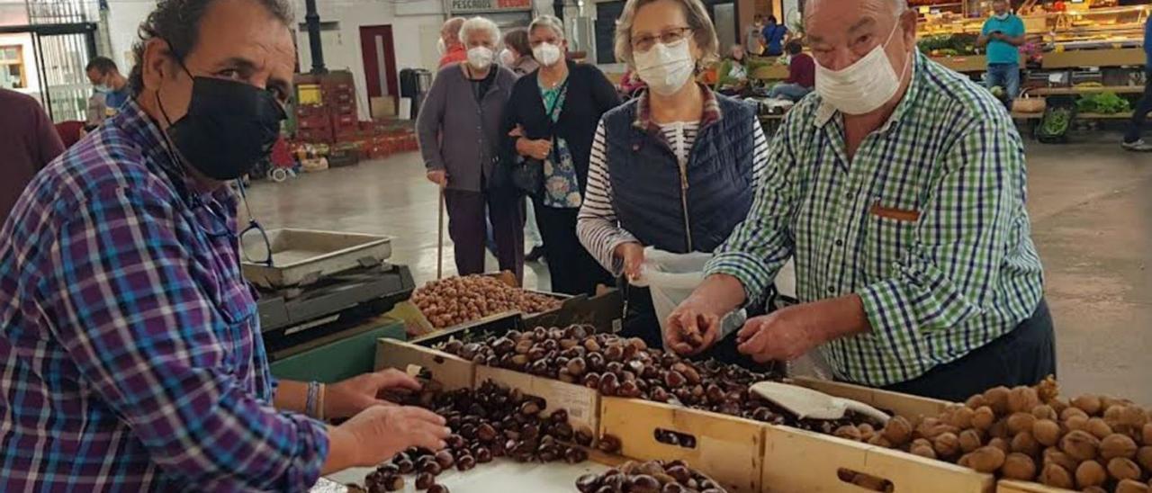 Paco Viera, a la izquierda, vendiendo castañas a Rosa Palacio y Adriano Ordieres, “Pichi”, en el último mercado celebrado en la plaza de abastos de Villaviciosa. | Vicente Alonso