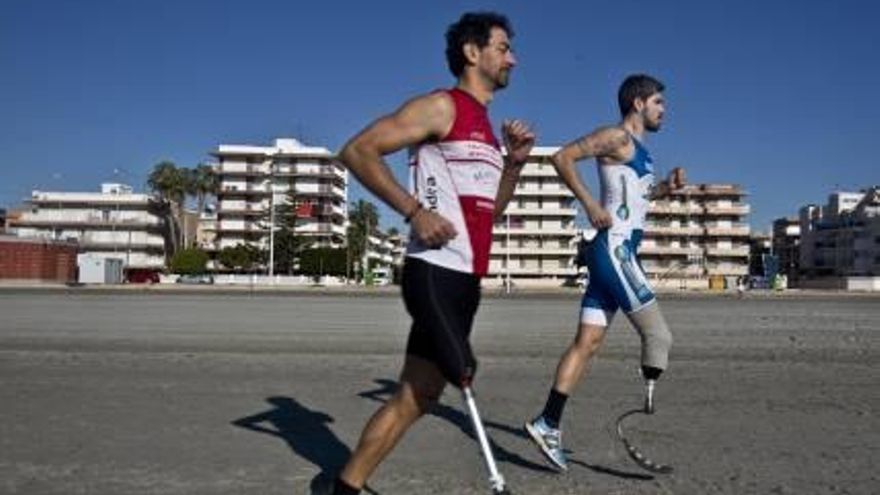 Ricardo Marín (de rojo) y Modesto Pascual, atletas de paratriatlón, corren en una playa de Santa Pola gracias a sus prótesis realizadas en  fibra de carbono.
