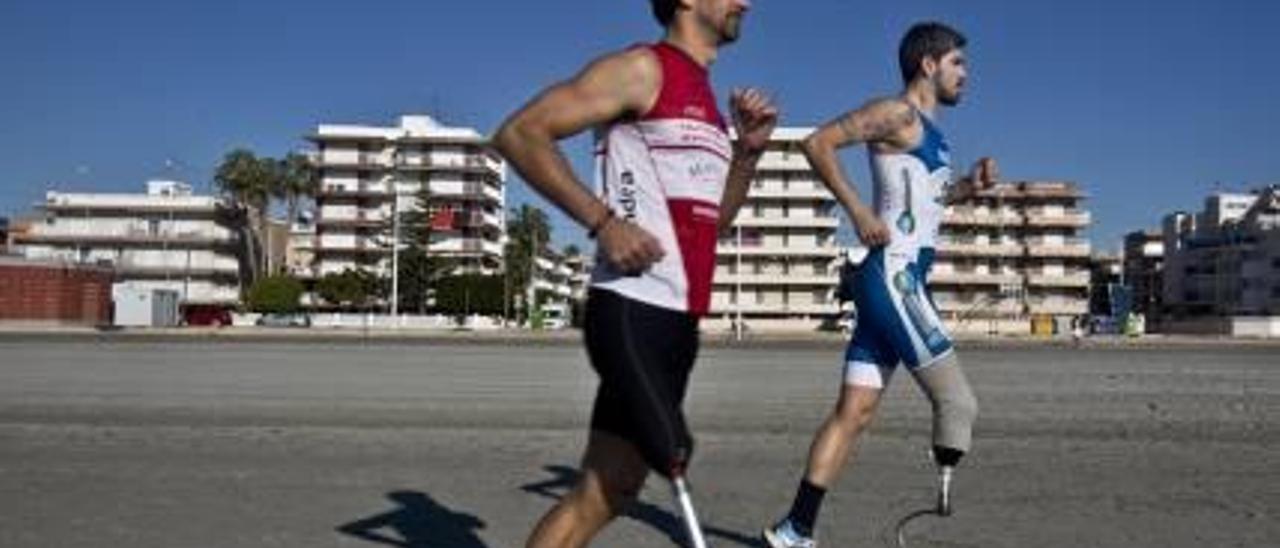 Ricardo Marín (de rojo) y Modesto Pascual, atletas de paratriatlón, corren en una playa de Santa Pola gracias a sus prótesis realizadas en  fibra de carbono.