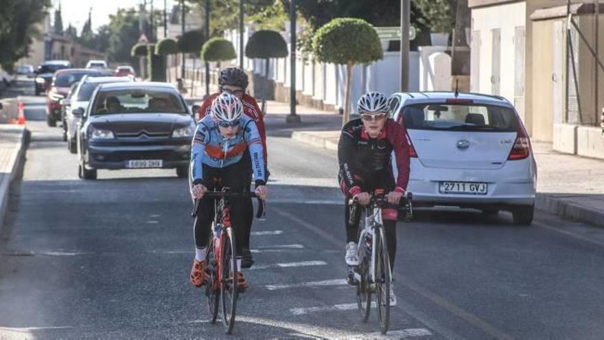 Tres ciclistas circulan por la calzada en obras de la CV-900 a su paso por el barrio del cementerio de Callosa de Segura.