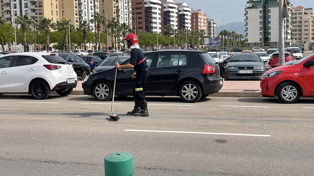 Un bombero limpia los restos de aceite de la calzada para evitar accidentes.