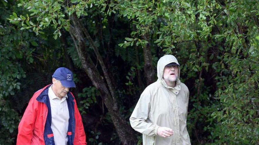 José Benito Suárez y el presidente Mariano Rajoy caminan bajo una intensa lluvia a la altura de la Aldea Labrega de San Martiño, en Meis. // Noé Parga