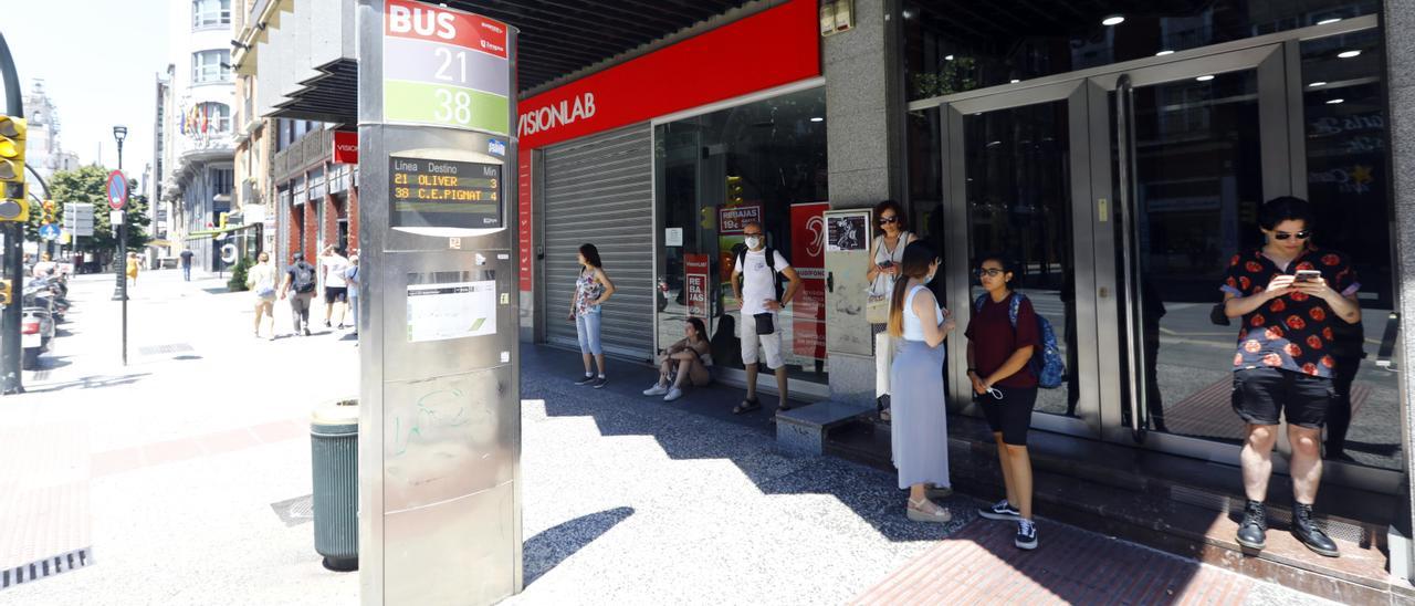 Los usuarios del bus se resguardan del sol a la sombra en una parada del Coso,. este miércoles en Zaragoza.