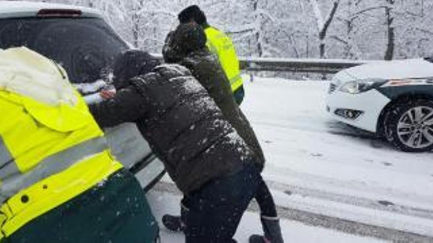 Agentes empujando un coche en la nevada.