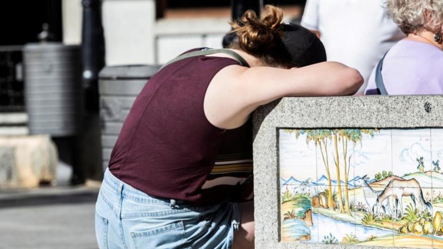 Una persona descansa apoyada en un muro