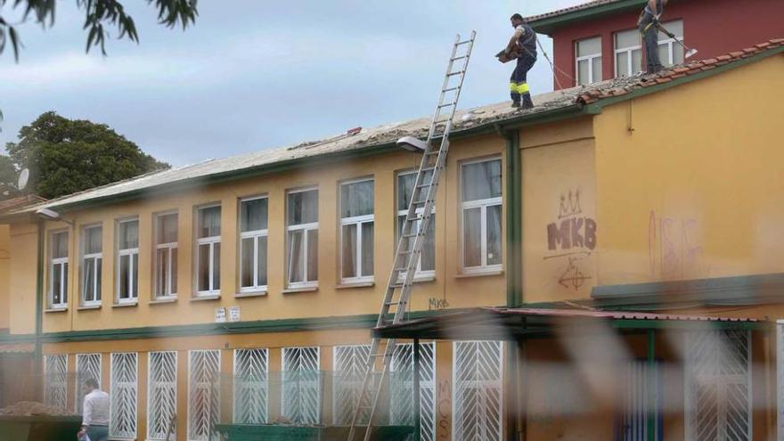 Dos trabajadores en el tejado del colegio de Infantil de Salinas, ayer por la tarde.
