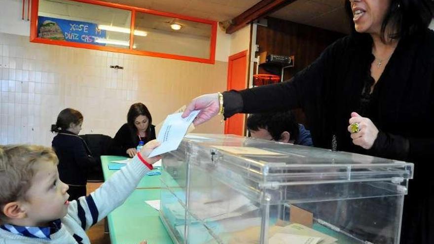 Arriba, una mujer vota en el Julio Camba de Vilanova con una diadema navideña. A la derecha, un niño vota por su madre en San Tomé (Cambados). // I.Abella