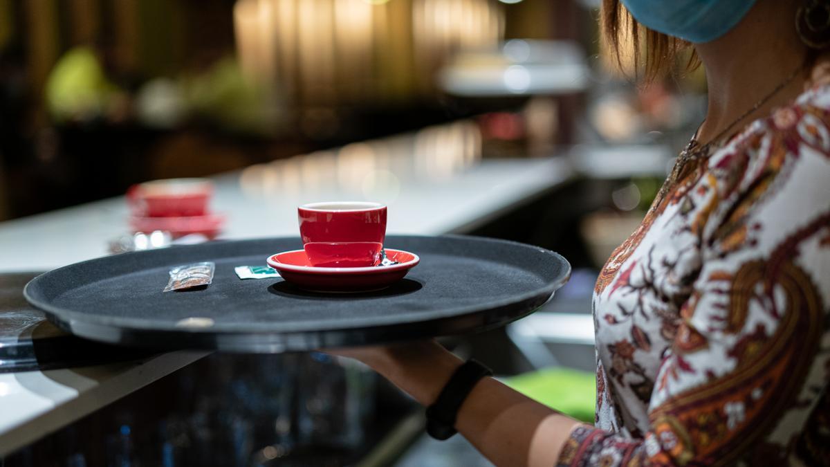 Una camarera sirve el café a un cliente.