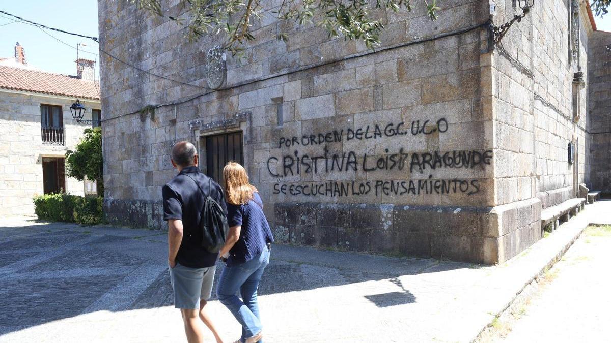 Una pareja observa la pintada de la iglesia de San Benito de Fefiñáns, en Cambados.