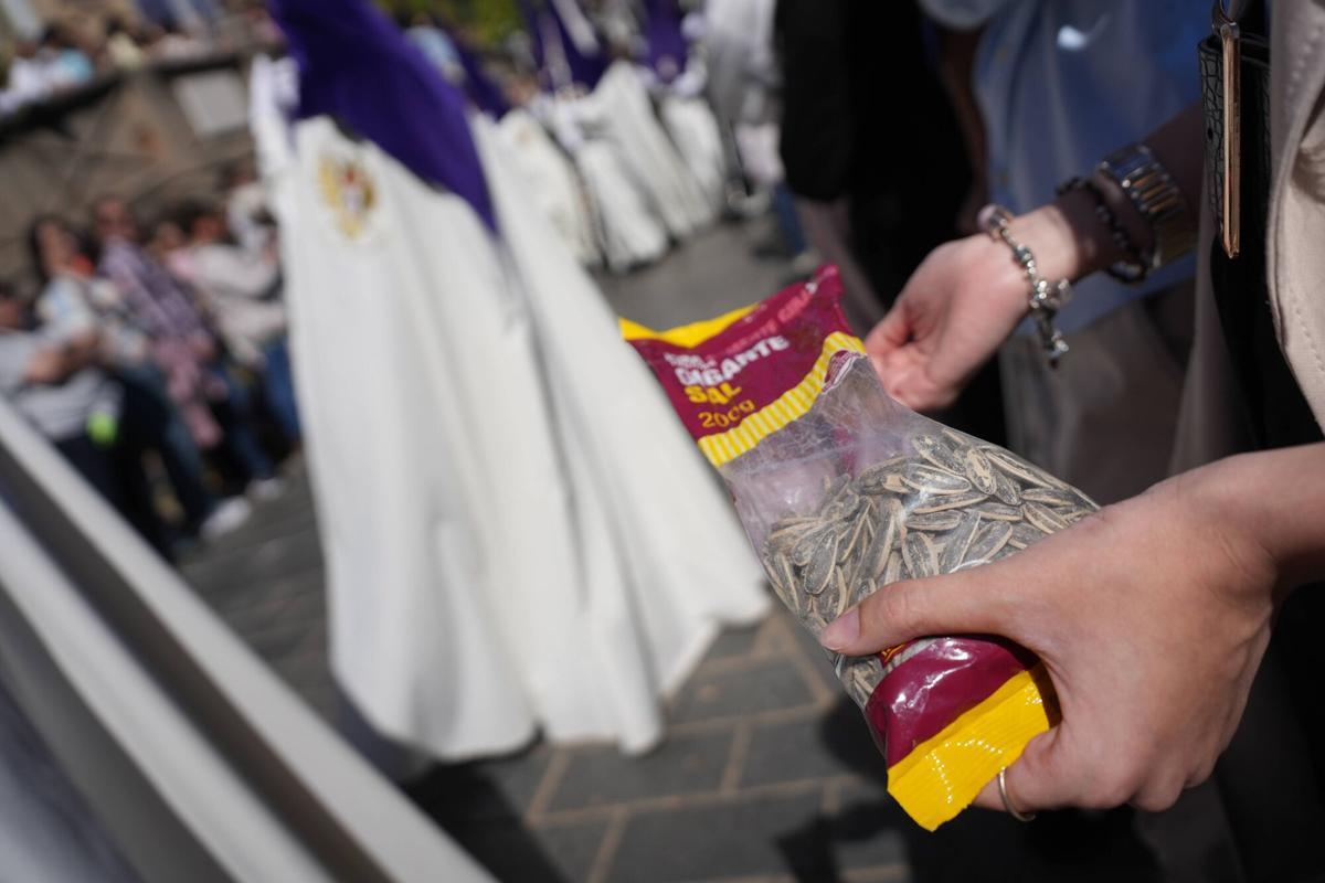 Una espectadora come pipas durante el paso de una procesión en Córdoba.