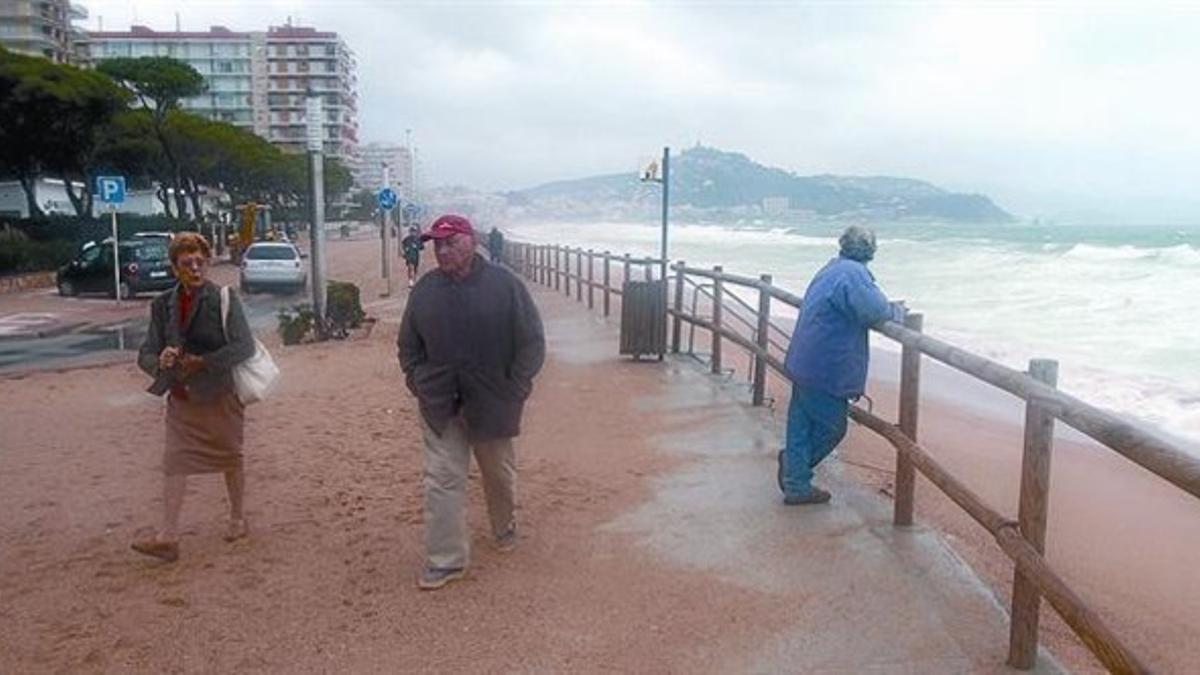 Un padre protege del oleaje a su hijo en una playa del Masnou, ayer.