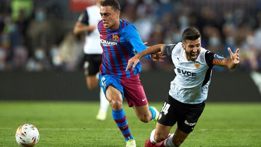 El capitán del Valencia, José Luis Gayá, cae ante el jugador del Barça Sergiño Dest. | EFE/ALEJANDRO GARCÍA