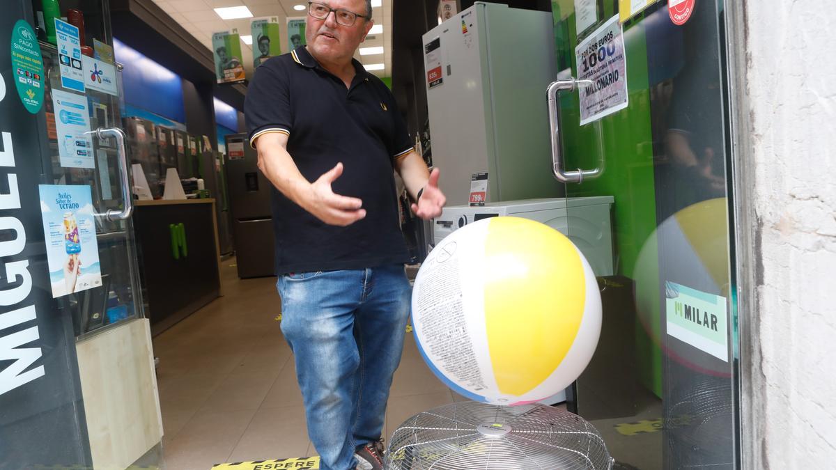 Miguel Cuervo junto a un ventilador en funcionamiento en su tienda de electrodomésticos de Avilés.