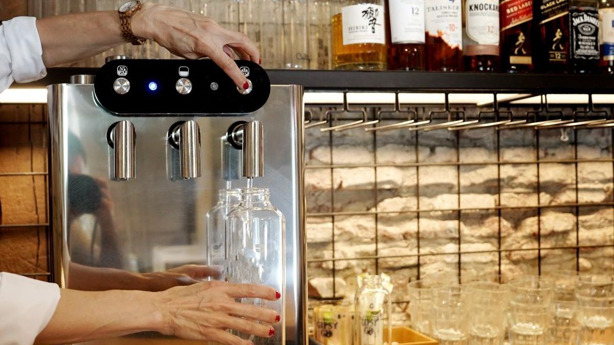 Una camarera llena una botella de agua purificada en un restaurante del centro de Madrid.
