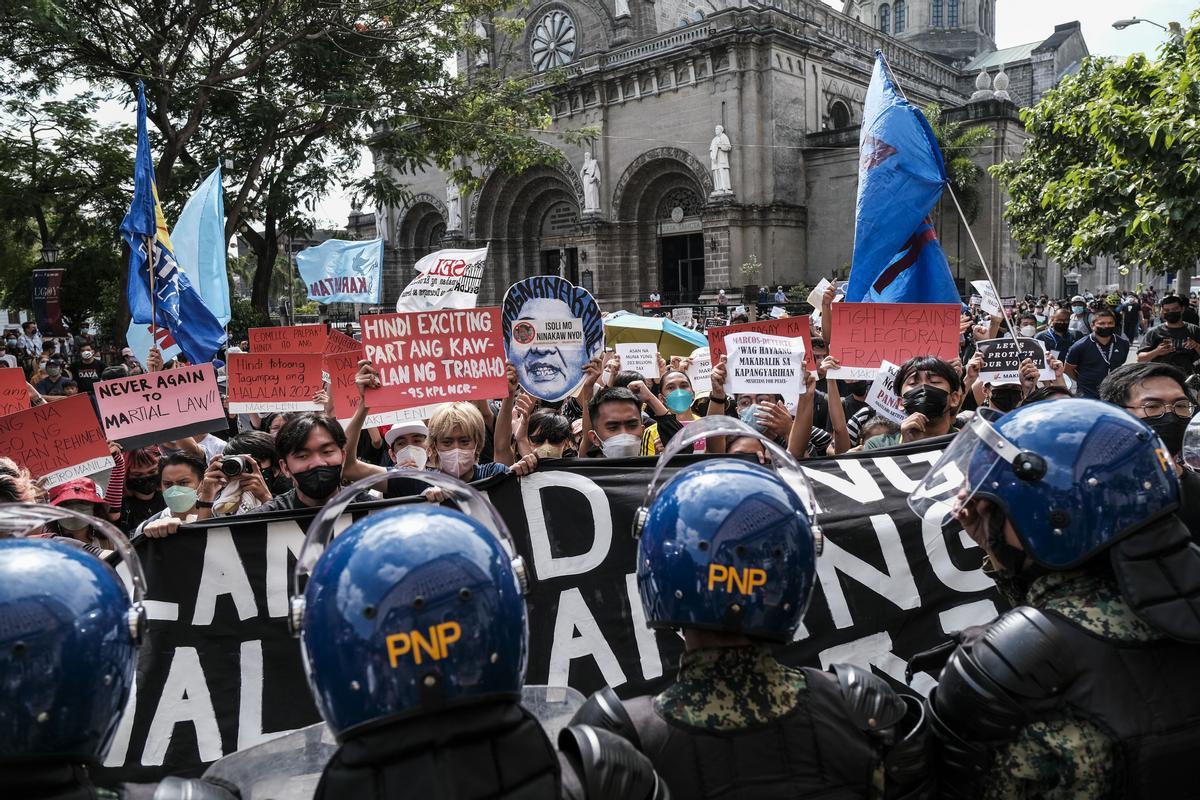 Manifestantes frente a un cordón de agentes de seguridad, frente a la Comisión de Elecciones en Manila